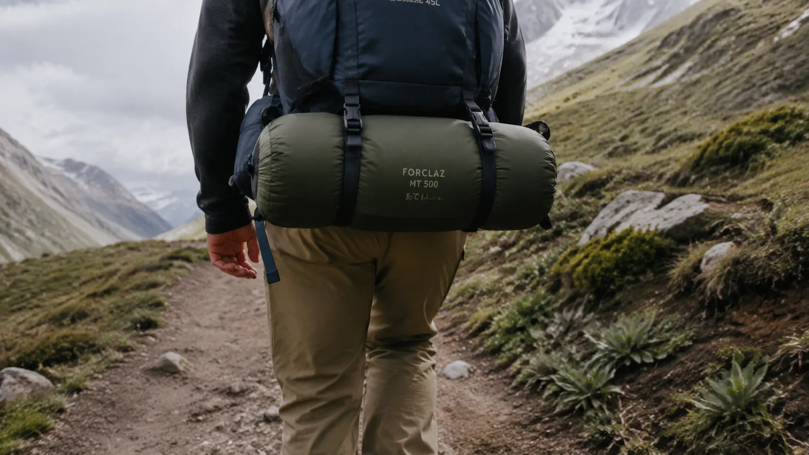 The Teton Sports Celsius sleeping bag compressed and strapped to the bottom of a backpack on a trail