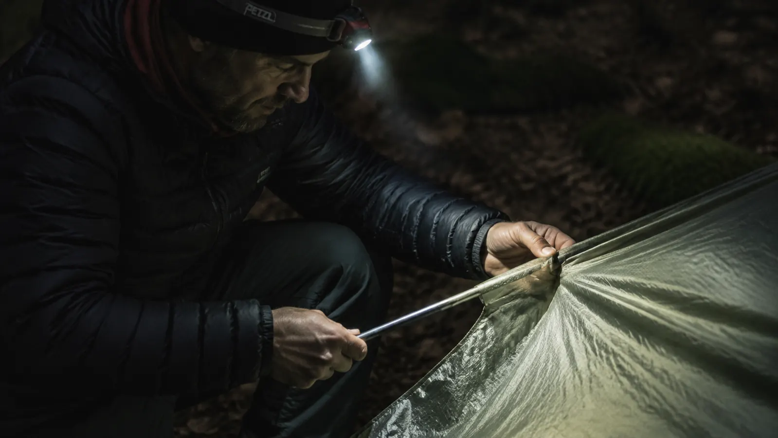Close-up of hands threading a tent pole through a sleeve on the Naturehike Cloud-Up fly in low light conditions