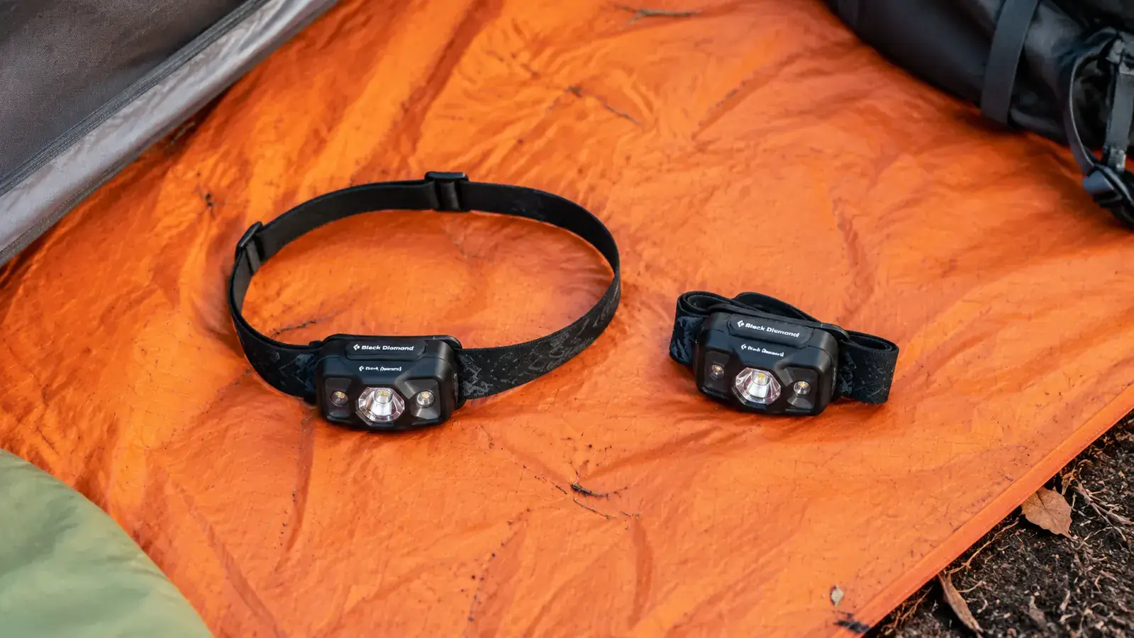 two LHKNL headlamps side by side on a tent floor showing the 2-pack value, one with headband extended and one folded
