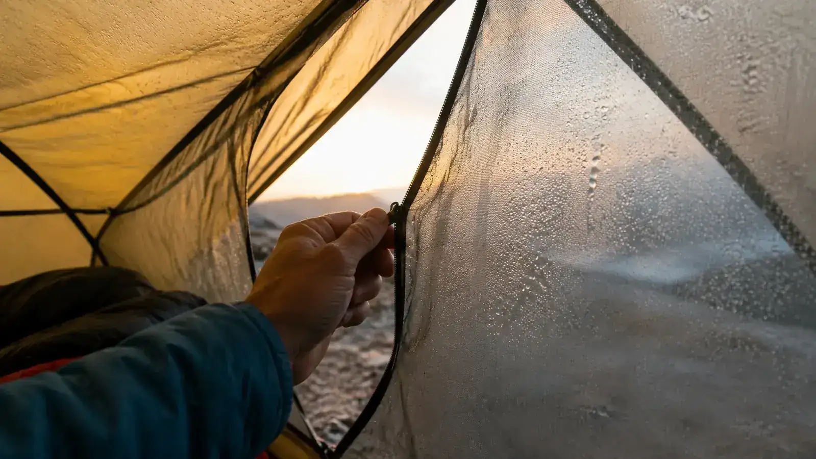 Close-up of a hand unzipping the Naturehike Cloud-Up tent door from inside at dawn