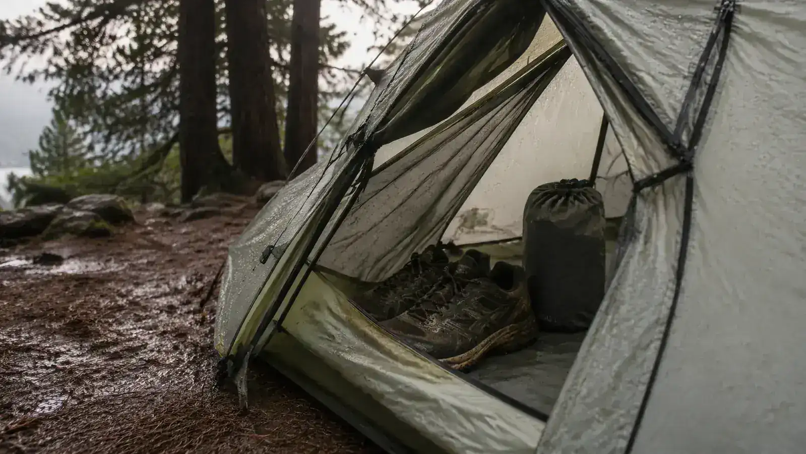 Naturehike Cloud-Up vestibule open with hiking boots and a dry bag stored inside on wet ground