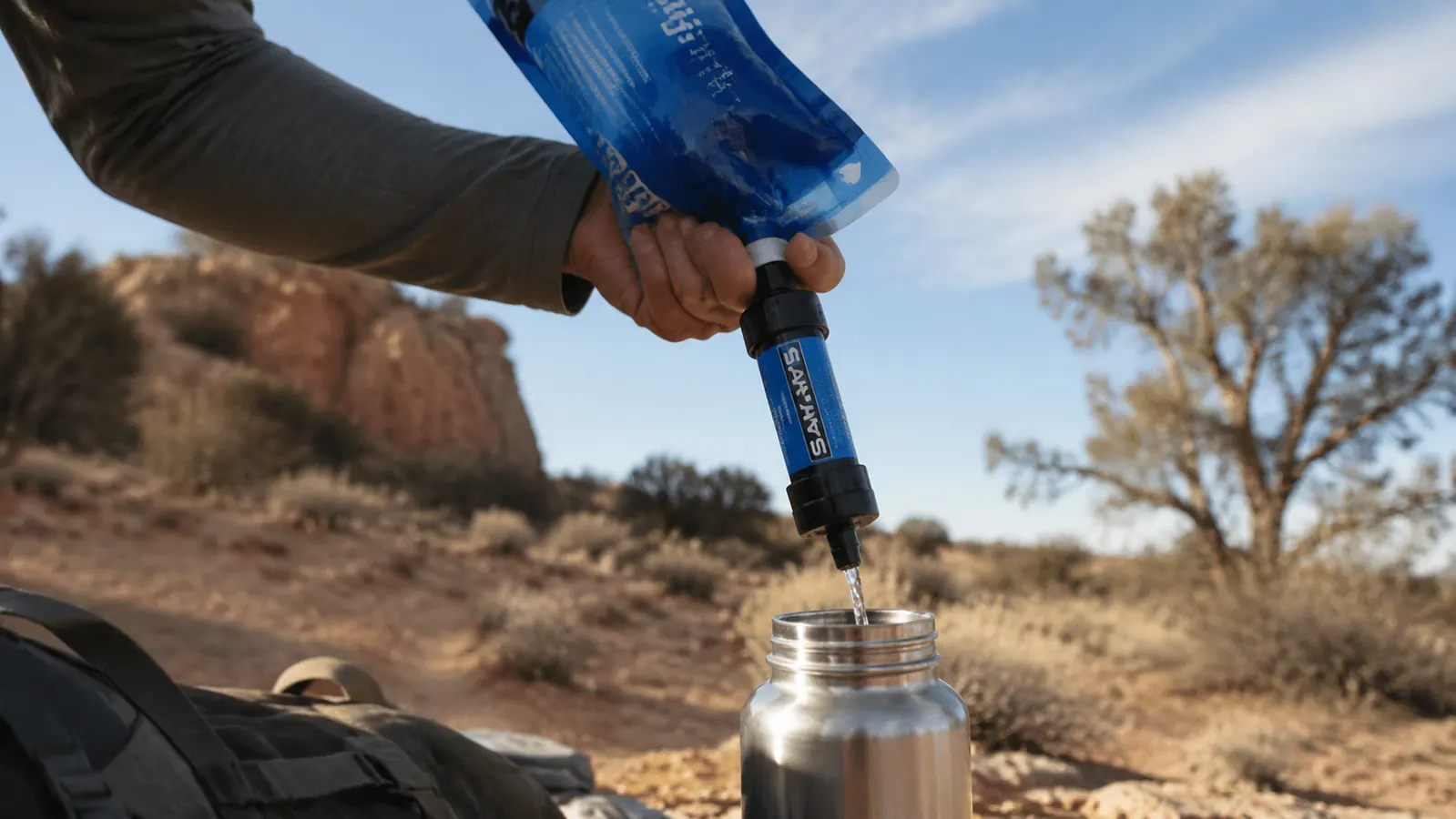Close-up of a Sawyer Mini filter attached to a squeeze pouch, water flowing through in the field