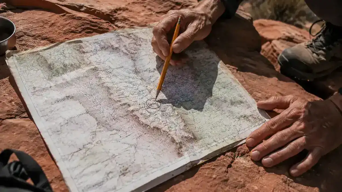 Topo map spread on a rock with a pencil marking a water source that was found dry