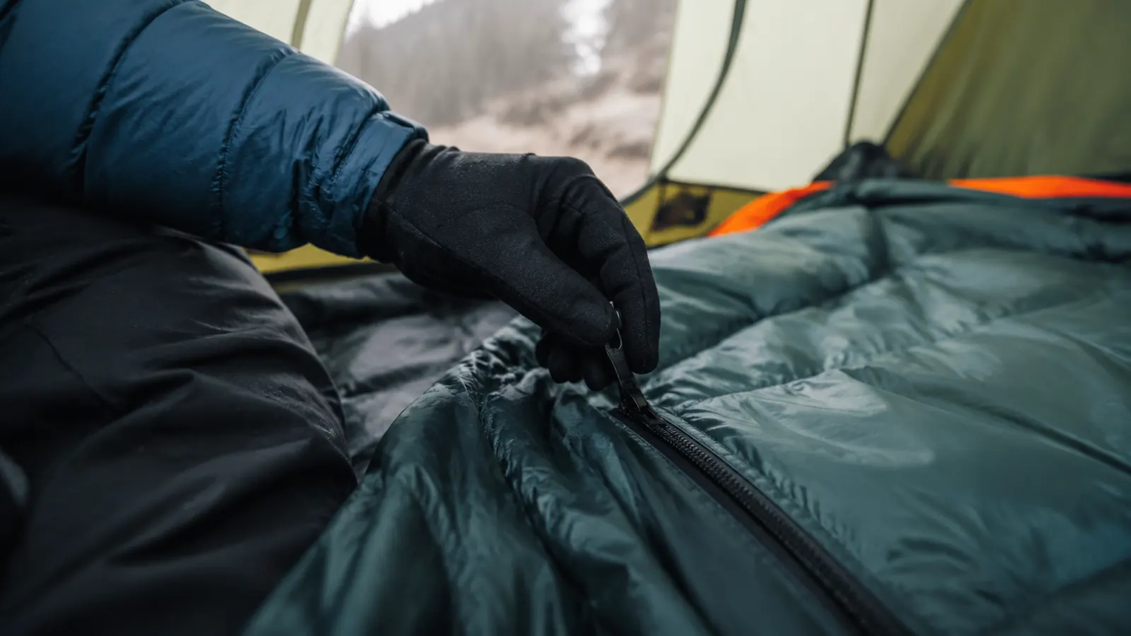 Hand gripping the side zipper of the Teton Sports Celsius sleeping bag, close-up detail shot